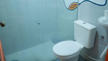 A bathroom with a white toilet, a glass shower enclosure, and a tiled wall with a decorative pattern.