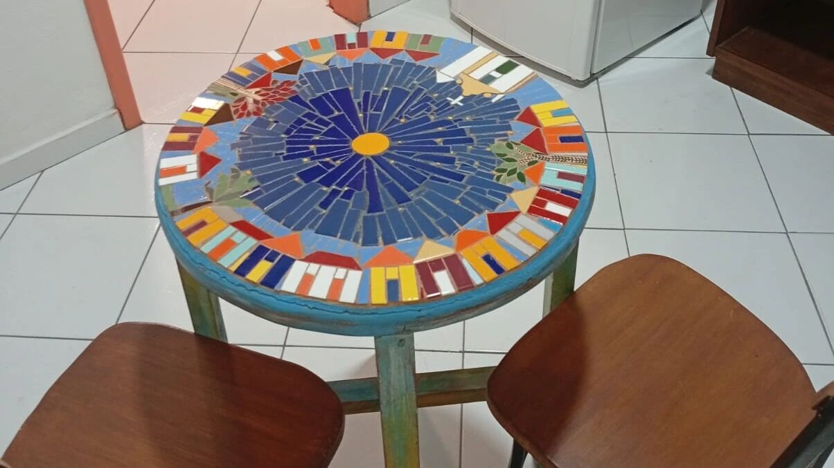 A round table with a colorful mosaic top surrounded by four wooden chairs.