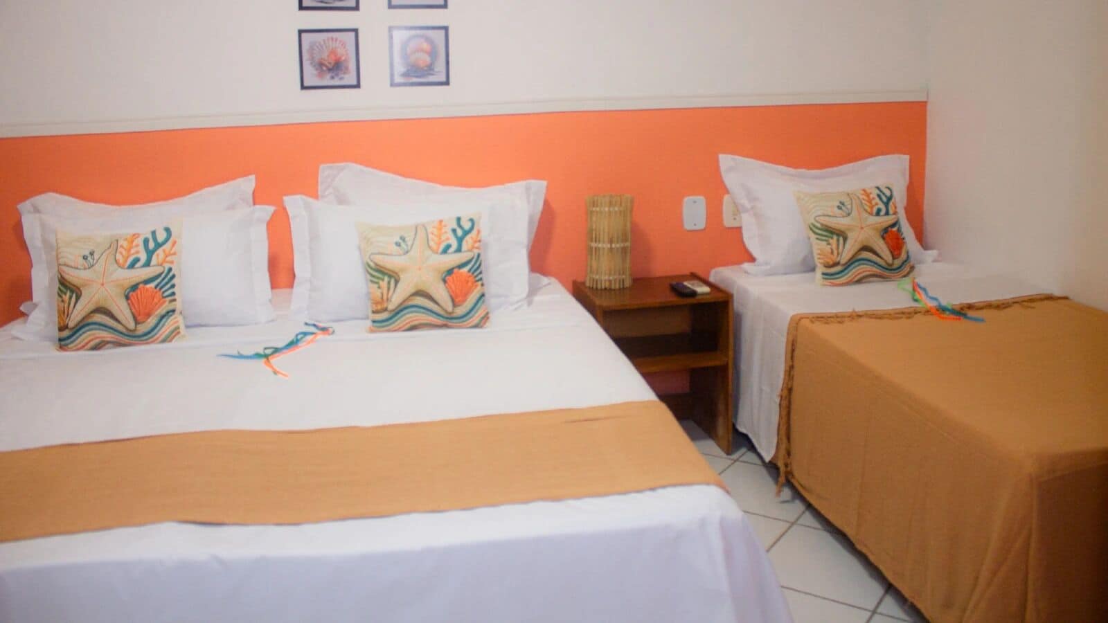 Een hotelkamer met twee bedden, elk voorzien van een witte spreidek en decoratieve kussens met zeethema's.