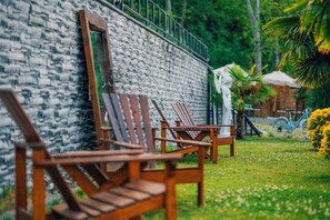 Wooden chairs and a bench against a stone wall in a garden setting. - MC Sapanca Hotel (Sapanca)