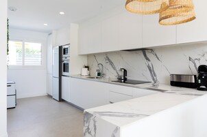 A modern kitchen with white cabinets, a marble backsplash, and a central island.