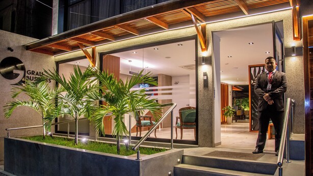 A modern hotel entrance with a staircase leading to the lobby, featuring a reception desk and seating area. - GRAU BUSINESS HOTEL (Piura)