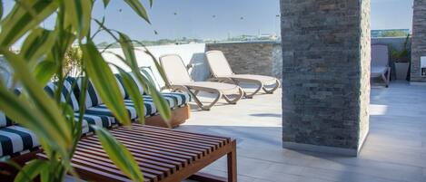Un área de terraza con sillones, un banco de madera y una planta en maceta.