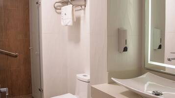 A modern bathroom with a white toilet, a sink with a mirror, and a shower area.