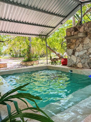 A covered swimming pool with stone walls and a metal roof, surrounded by greenery. - Santa Clara Ecological Reserve. Exclusive hotel in the jungle. Valladolid Yucatan. (Vallladolid)