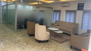 A modern office space with a glass partition, a sofa, two armchairs, and a coffee table. - Victia Suite and Lounge (Ijebu Ode)