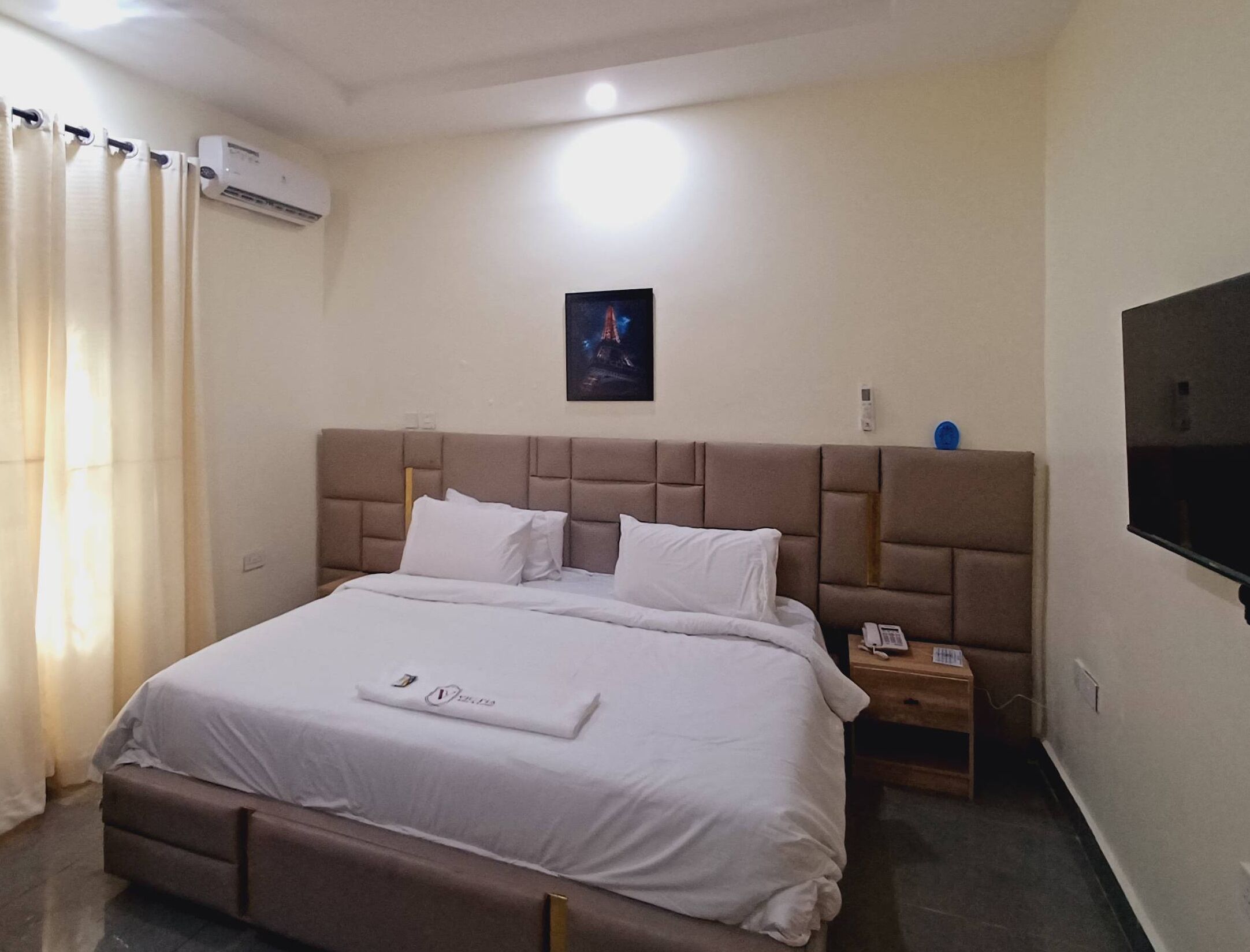 Une chambre d’hôtel équipée d’un lit, d’une table de chevet, d’un téléviseur et d’un appareil de climatisation.