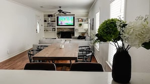 Un coin repas avec une table et des chaises en bois, un téléviseur et une cheminée.