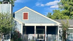 Une maison de plain-pied avec un porche avant couvert, une cheminée et le numéro « 109 » sur le mur avant.