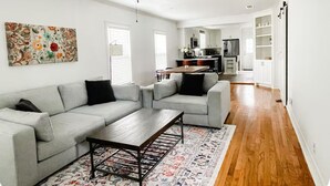 Un salon spacieux avec un canapé gris, une table basse et un ventilateur de plafond.