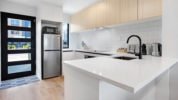 A modern kitchen with white cabinetry, stainless steel appliances, and a central island.