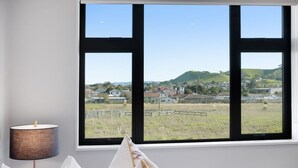 A room with a large window offering a view of a green landscape and buildings.