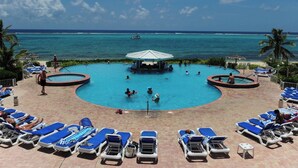 Zona de piscina con sillones de descanso, una fuente central y vistas al océano.