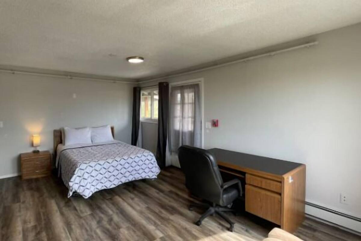 A bedroom with a bed, bedside table, desk, and chair.