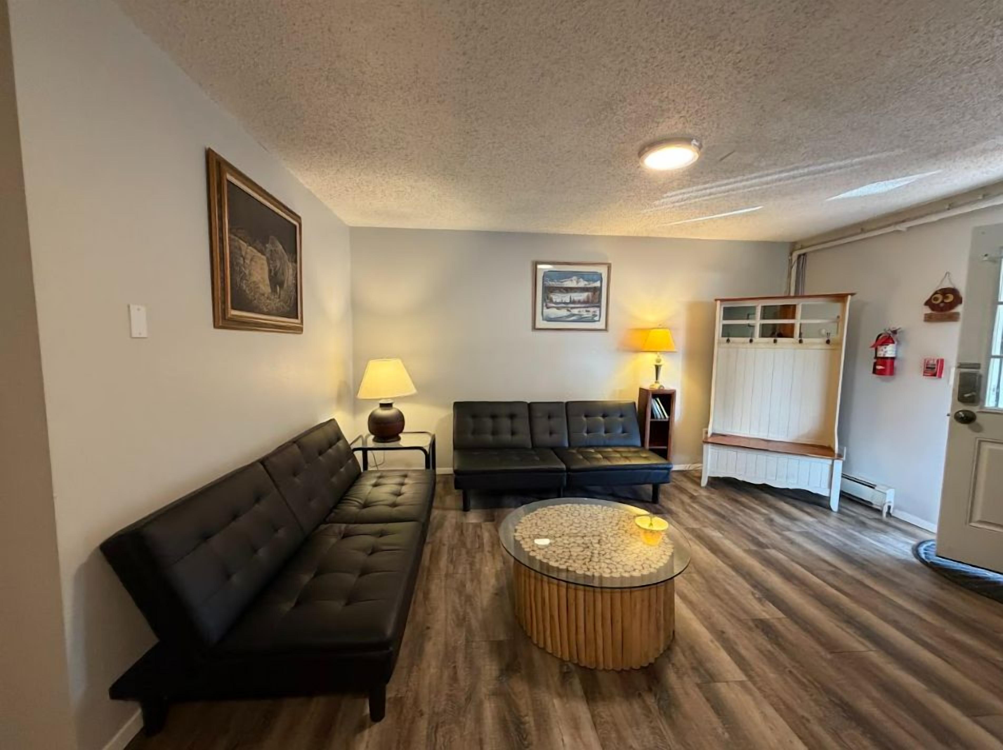 A living room with a black sofa, a round coffee table, and a black couch.