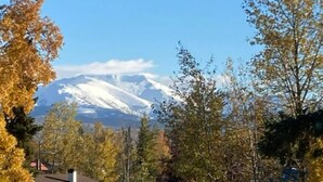 A mountain with snow-capped peaks in the background, surrounded by autumn-colored trees. - Great North Lodging (Anchorage)