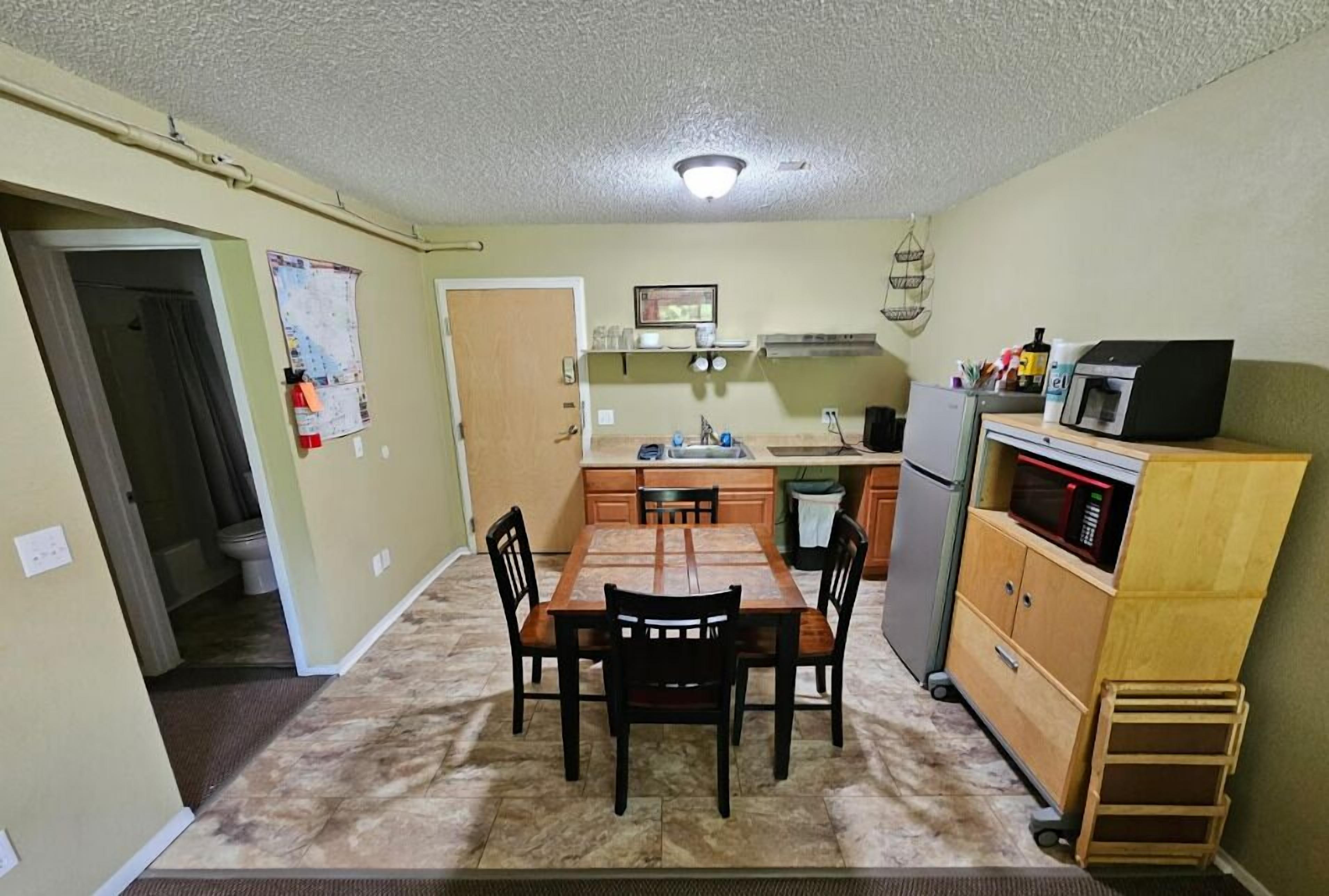 Une cuisine compacte comprenant une table à manger, des chaises, un four à micro-ondes et un réfrigérateur.