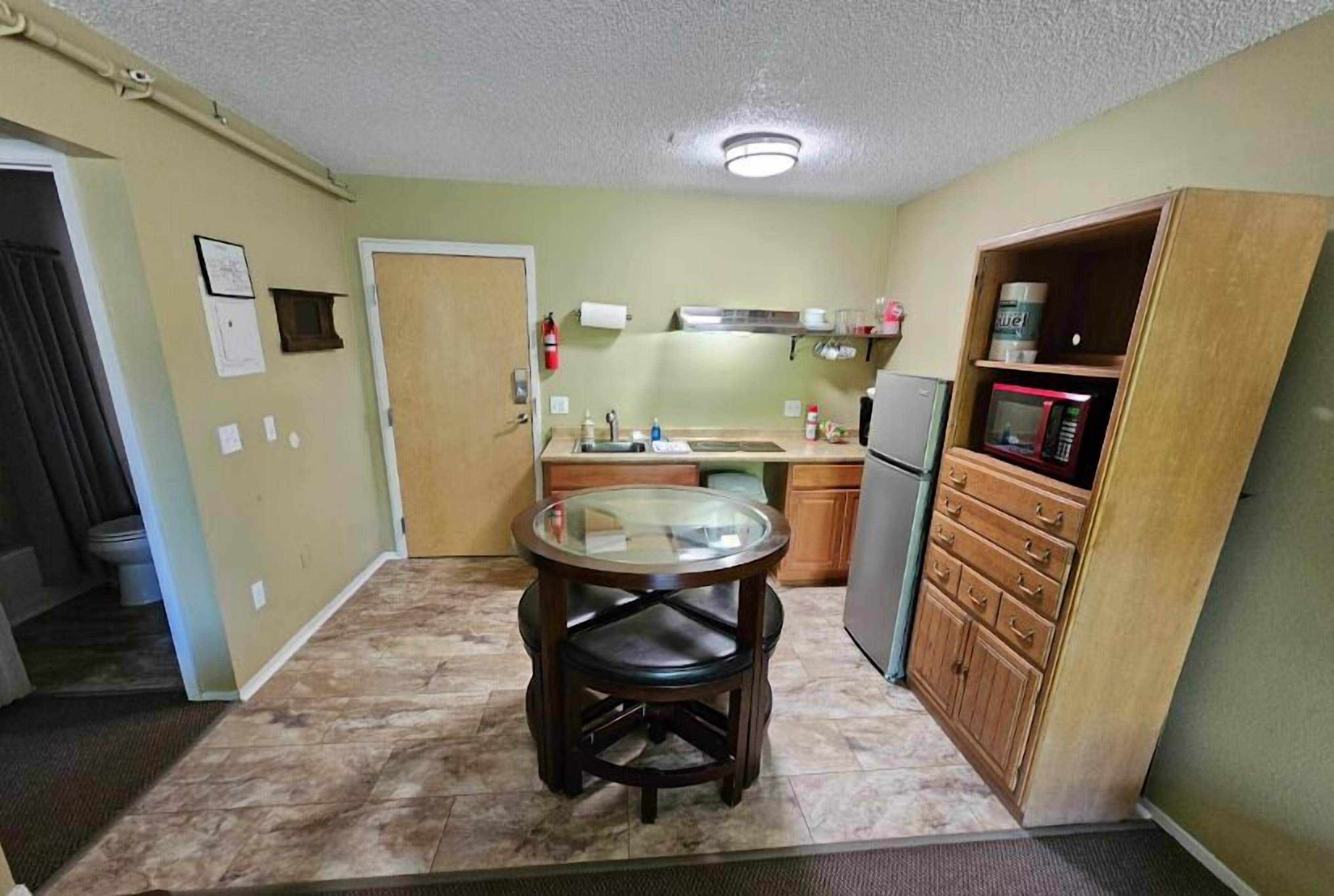Una cocina compacta con una mesa redonda, un refrigerador y un microondas.