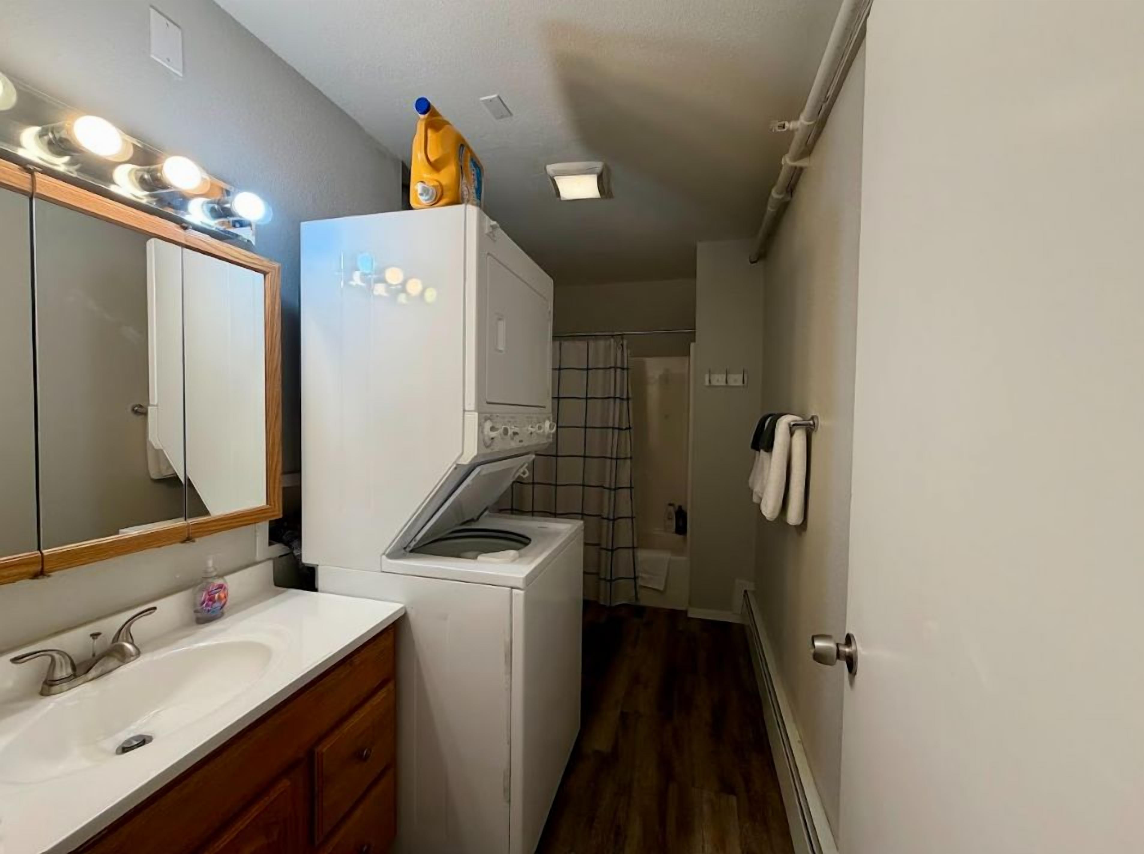 Une petite salle de bain comprenant un lavabo, un miroir et un lave-linge blanc.