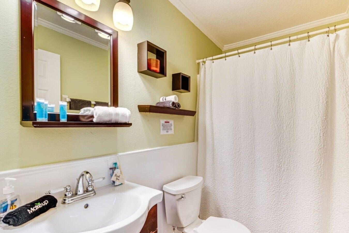 A bathroom with a sink, toilet, and shower curtain.
