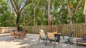 Un patio al aire libre con un brasero, sillas de mimbre y un dardo.