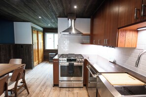 A modern kitchen with wooden cabinets, a stainless steel stove, and a built-in oven. - Oz Lodge: Alice Chalet -Brand new, Alaskan chic chalet! (Seward)