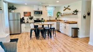 A modern kitchen with a central island, white cabinetry, and a stainless steel refrigerator. - Sandy Pond Cozy Getaway (Pulaski)