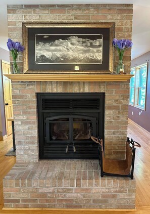 A fireplace with a framed picture above it, flanked by vases with purple flowers. - Honey Homestead, 6 bedrooms, sleeps 11! Working farm. Perfect place to unplug. (Salem)