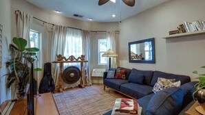 A cozy living room with a sofa, a small table, a lamp, and a guitar.