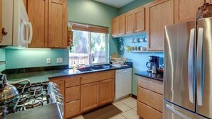 A kitchen with wooden cabinets, a stainless steel refrigerator, a dishwasher, and a gas stove.