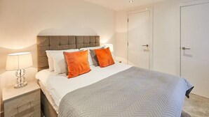 Une chambre à coucher avec un lit, des tables de chevet et une porte.