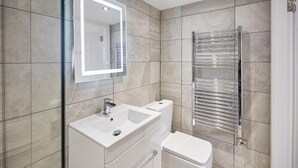 Une salle de bain moderne avec un grand miroir, un lavabo, des toilettes et un porte-serviettes.