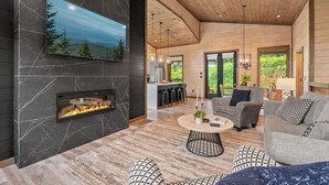 Ein modernes Wohnzimmer mit Kamin, einem an der Wand montierten Fernseher und einer gemütlichen Sitzecke mit rundem Couchtisch.