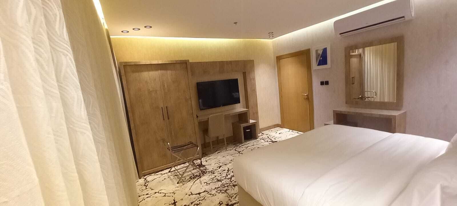 A hotel room with a bed, a TV, a wardrobe, and a mirror.
