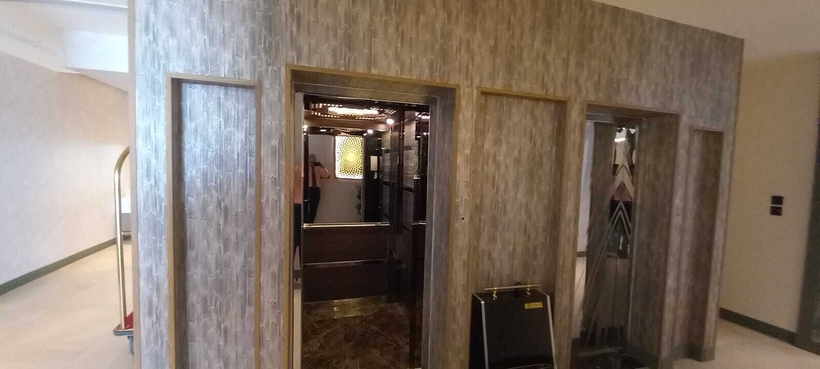 Ein Aufzug mit Holzausstattung, einem sichtbaren Notruftelefon und einem kleinen Gepäckwagen.