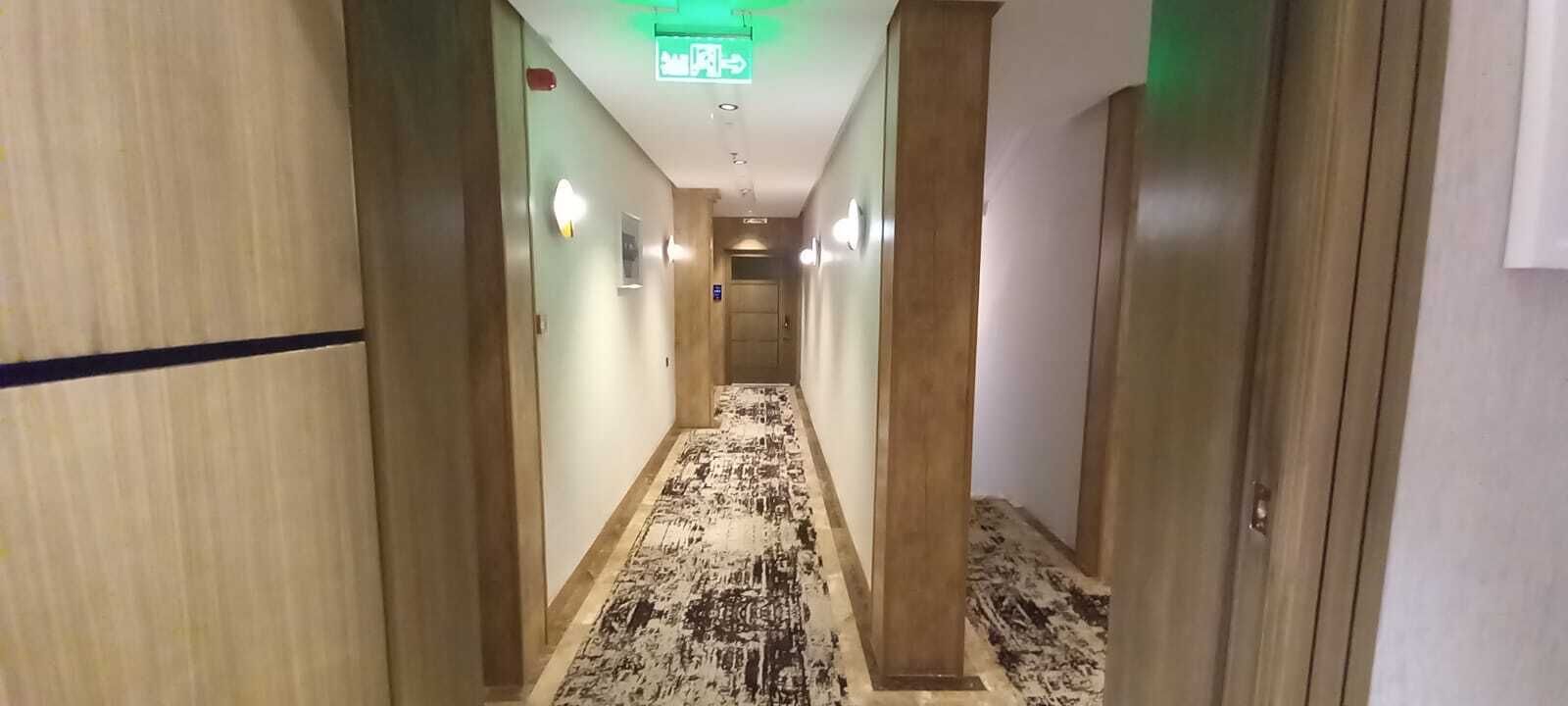 A hallway with wooden walls and a patterned carpet.
