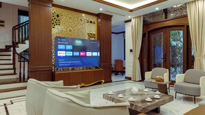 Una sala de estar moderna con un televisor de pantalla plana mostrando servicios de transmisión, una escalera y vistas al exterior.