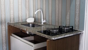 A kitchen with a granite countertop, a sink, and a gas stove. - OYO Hotel Tbs (Manacapuru)