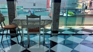 A room with a checkered floor, a table with a lace tablecloth, and two chairs. - OYO Hotel Tbs (Manacapuru)