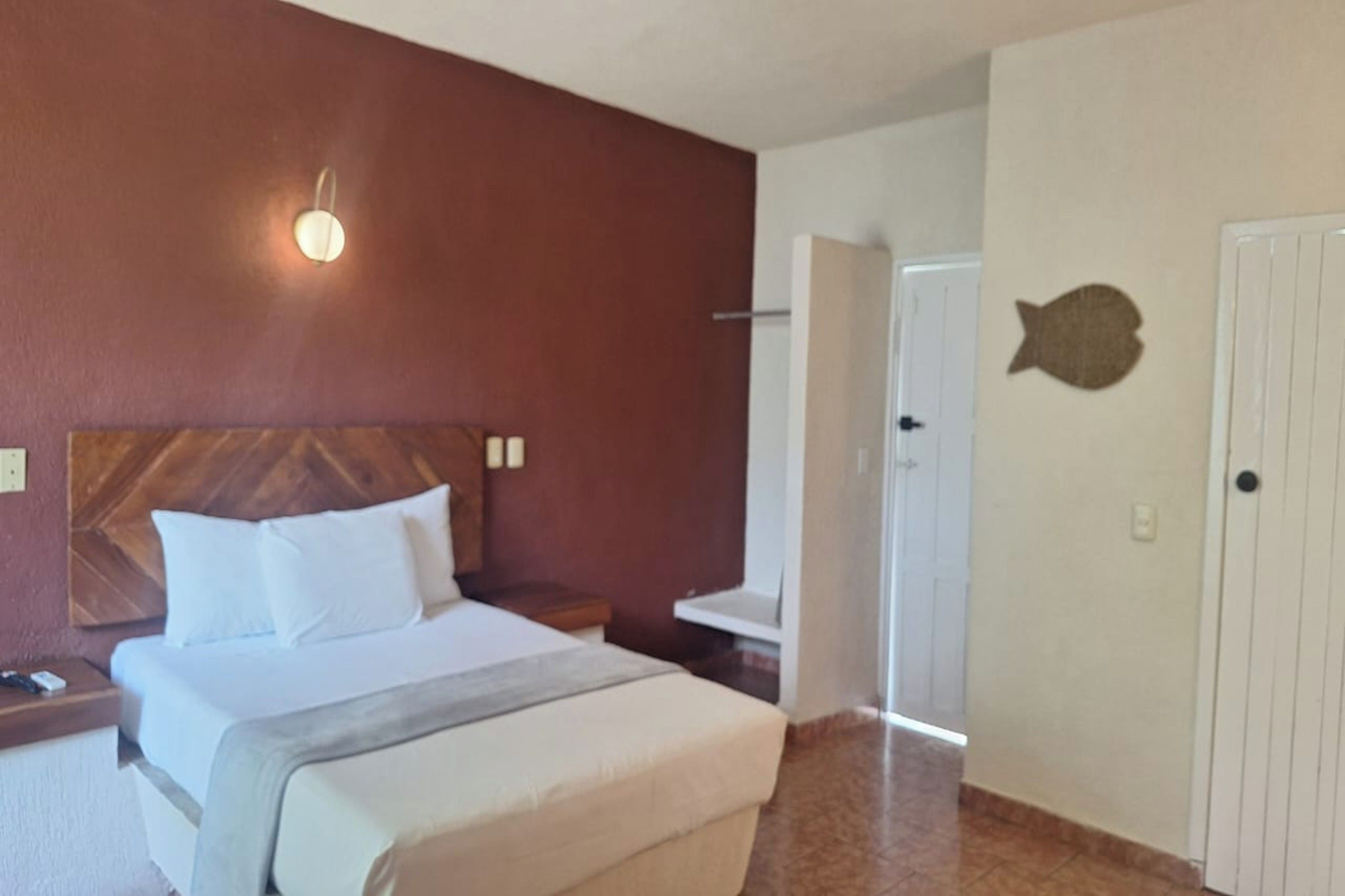 Habitación de hotel con cama, mesita de noche y lámpara fijada a la pared.