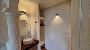 A bathroom with a white sink, a round mirror, and a towel rack. - Hotel Rolovi Cancun (Cancun)