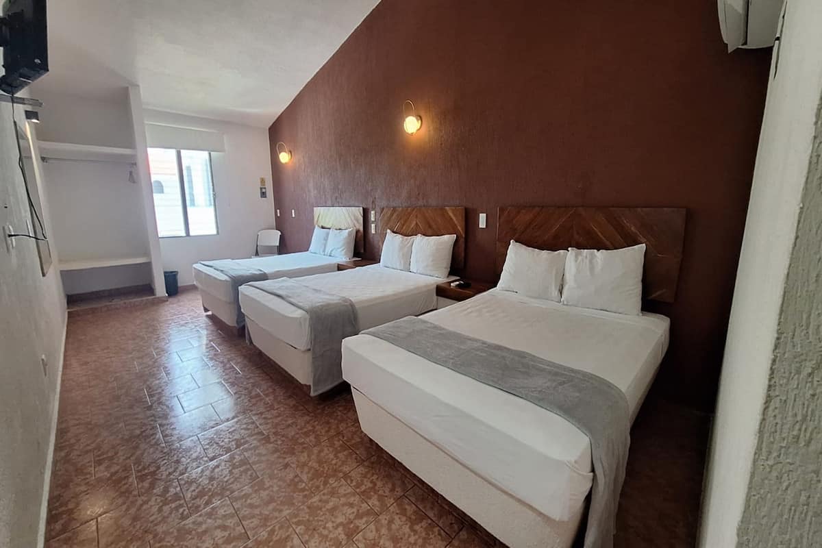 A hotel room with two beds, a window, and a wall-mounted TV.