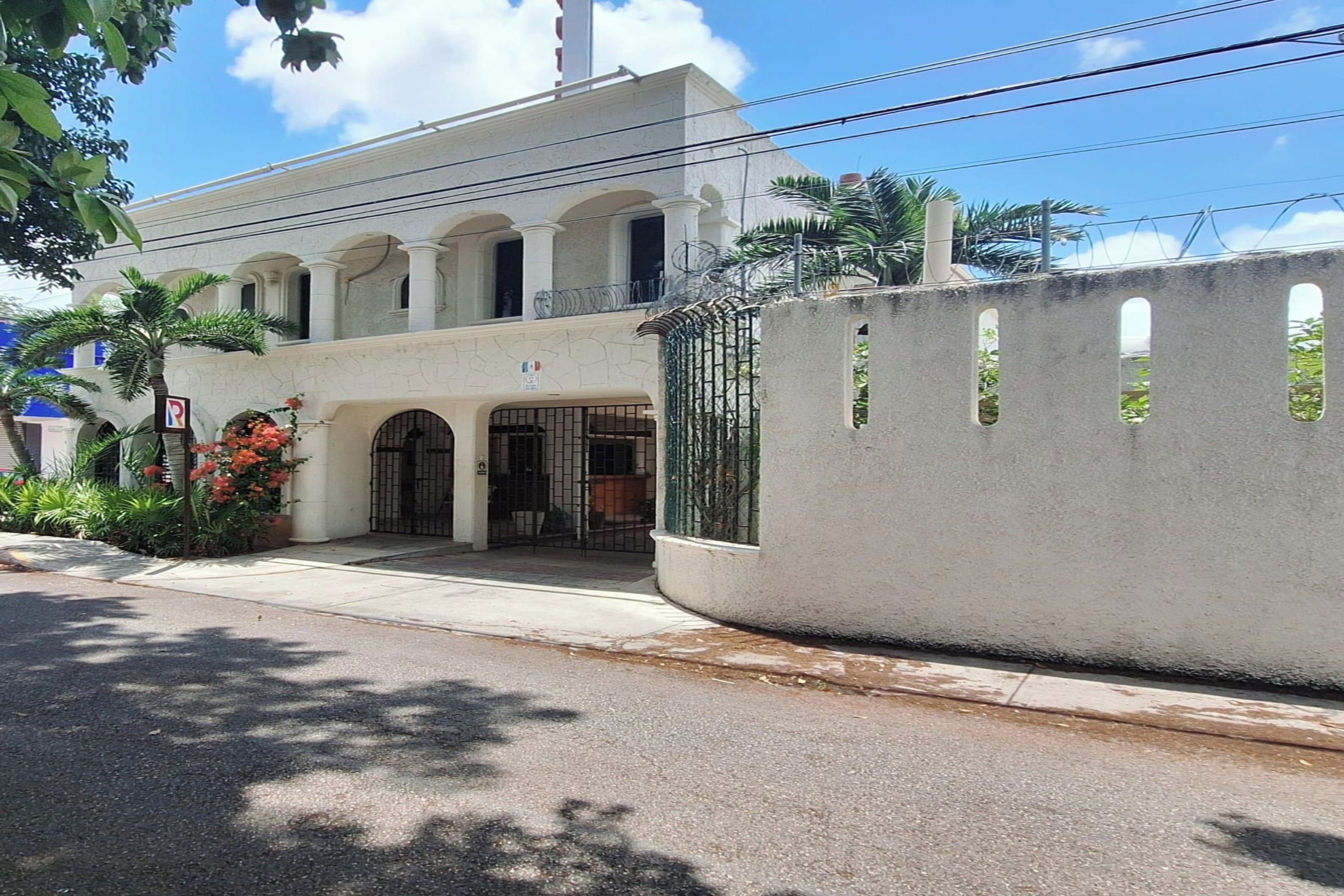 A building with a white facade, multiple arches, and a gated entrance.
