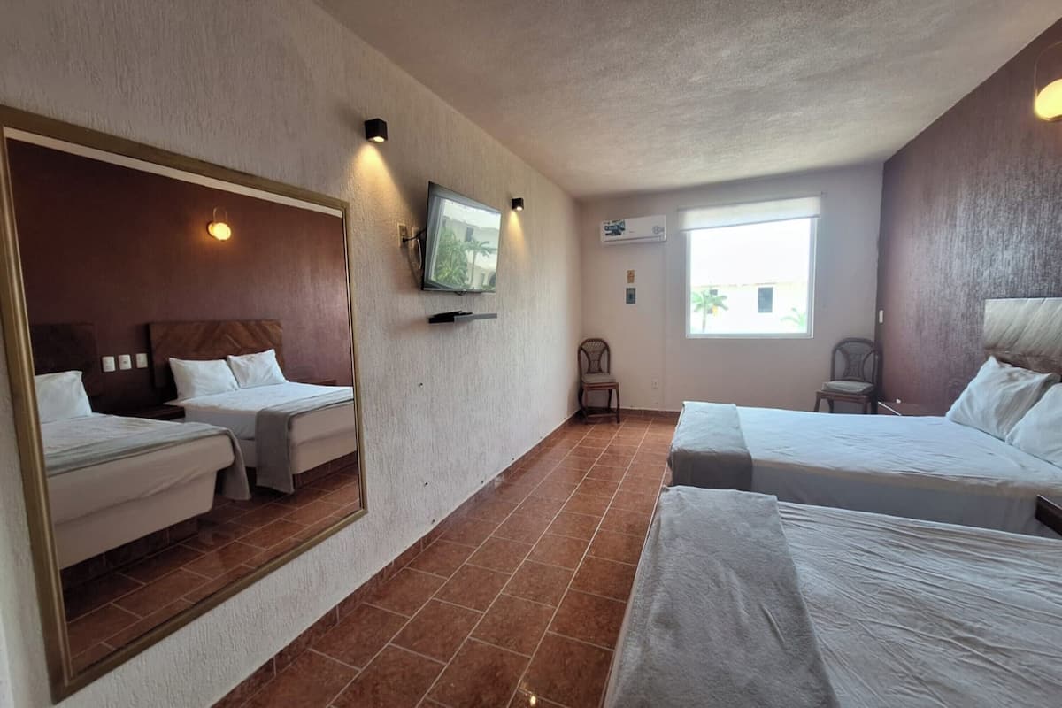 A hotel room with two beds, a large mirror, a television, and a window.