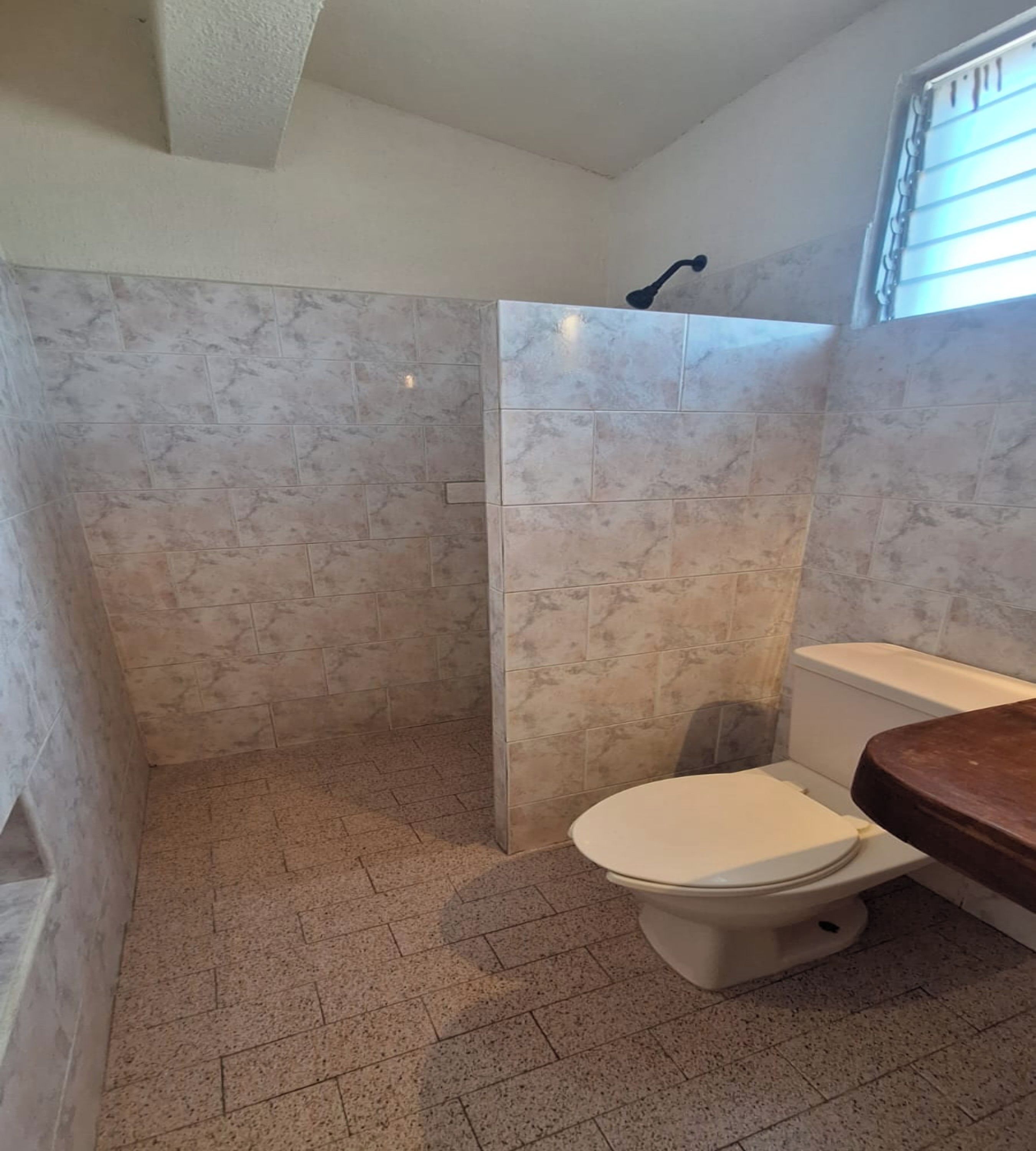 Un baño con inodoro, ducha y paredes de azulejos.