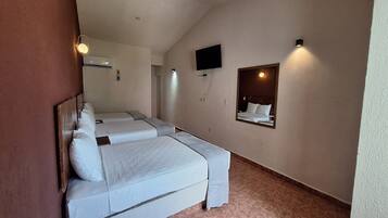 A hotel room with two beds, a television mounted on the wall, and a small mirror above the beds.