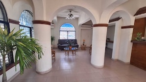 A spacious lobby with high ceilings, arched columns, and a large window providing natural light. - Capital O Hotel Rolovi Cancún (Cancun)