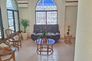 A seating area with a sofa, two chairs, a glass-top coffee table, and potted plants. - Hotel Rolovi Cancun (Cancun)