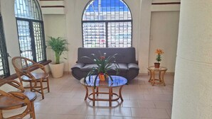 A spacious indoor area with a grey sofa, two wooden chairs, a glass coffee table, and potted plants. - Capital O Hotel Rolovi Cancún (Cancun)