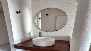 A bathroom with a white sink, a round mirror, and a wooden countertop. - Hotel Rolovi Cancun (Cancun)